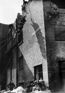 Casualty Prints: Firemen lower an injured man from the roof after rescuing him from the debris follow a V1