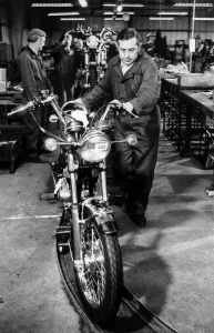 00101 Prints: The first of many hopes. Mr. Don Yielding as he wheels a semi-completed motor cycle on to