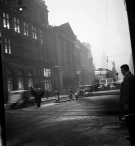 Fog scenes in the Strand. A policeman directs the traffic in the winter gloom