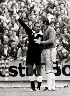 Footballer Jimmy Rimmer is booked by referee for marking the pitch
