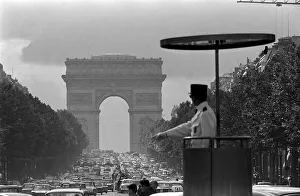 Paris Prints: France Paris - a Gendarme officer looks over the traffic at the Arc de Triomphe