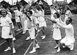 00199 Prints: Fred Perry Tennis Player teaching young children how to serve a tennis ball
