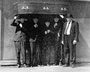 Coffins Prints: Furneral Directors using a coffin to stay dry as it pours down with rain Circa 1990