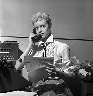 General office scene: Secretary taking notes and answering the phone in a Birmingham