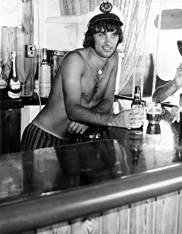 George Best Footballer in a sailors cap behind the bar in his favourite pub in Palma Nora