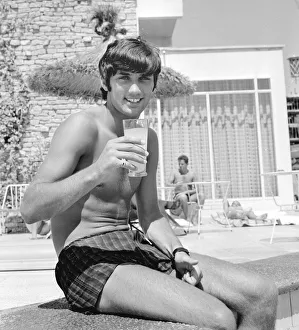 Sporting Legend Prints: George Best relaxing on holiday with a drink and sitting on the edge of a swimming pool