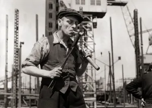 Waistcoat Prints: George Howard hand rivetter lights a cigarette from a white hot rivet
