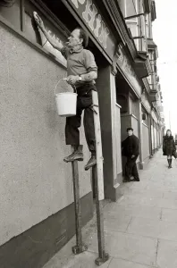 George Pettican Window Cleaner on Stilts cleaning windows on the front of his shop in