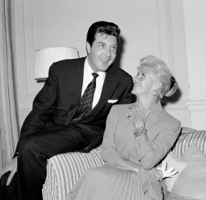 Square Prints: Ginger Rogers sitting on a couch laughing with David Hughes May 1959