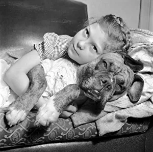 Girl lying down on the sofa with a boxer dog. December 1953 D7354-001