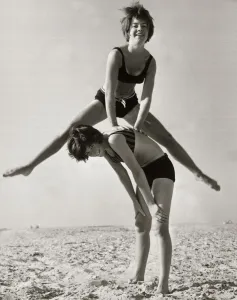 Emotions Prints: A girl performs an acrobatic leap frog over her friend as they play together on the beach