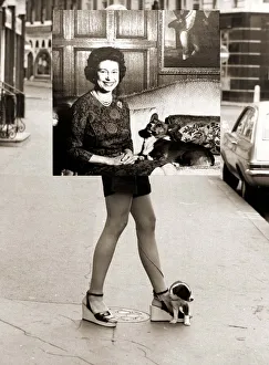 Girl wearing hotpants carrying a photograph of Queen Elizabeth to an exhibition