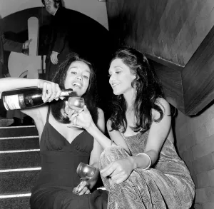 00038 Prints: Two girls sitting on the steps pouring a drink during a Christmas party December
