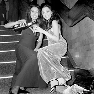Two girls sitting on the steps pouring a drink during a Christmas party December