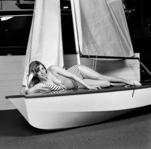 Swimsuit Prints: Top glamour model Stephanie McLean posing lying down in a sailboat January 1975