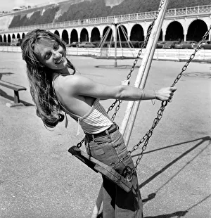 Glamour model wearing a striped vest top and a pair of jeans as she poses on a swing in a
