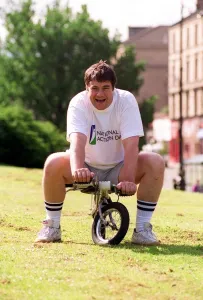 Gordon kennedy tv presenter sitting on a tiny bike at the kelvin sports arena