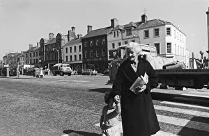 Northern Ireland Prints: A grandmother and her grandaughter crossing the main road in Lurgan after paying a visit