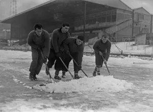 Grounds staff at Bristol Rovers Eastville Stadium struggle to clear snow from the pitch