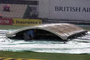 Groundsman Peter Marron Shelters From The Rain Under The Covers At Old Trafford