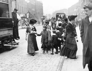 A group of children ask a female tram passenger for her used ticket after she descended