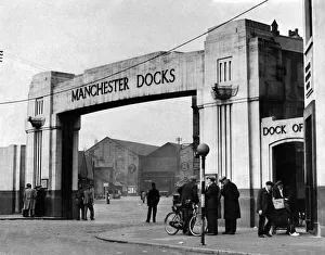 Docks Prints: Only a few groups of men stand chatting at the gate of a deserted Manchester dock May