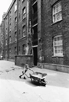 Images Dated 11th May 1976: Two and a half year old Darren Haydn plays with his wheelbarrow outside the Great Eastern