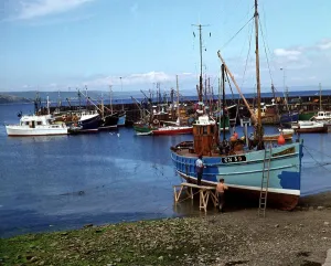 Harbour at Carradale Argyll Scotland Two fishermen are painting their boat blue