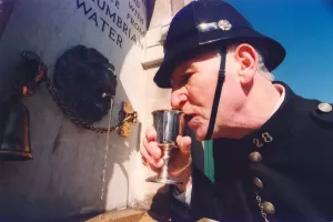 Harry Wynne dressed as a police sergeant from 1913 takes a drink from the newly installed