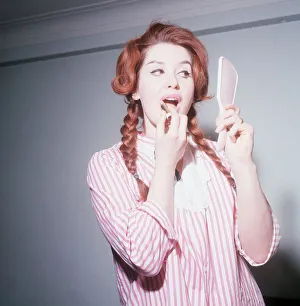 Heller Toren model actress 1964 puting on lipstick holding hand mirror pink striped shirt