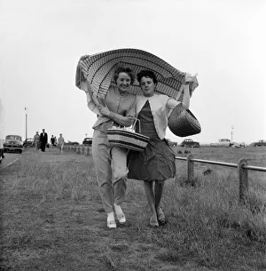 00039 Prints: Holidaymakers covering their heads run for cover after being caught in a shower