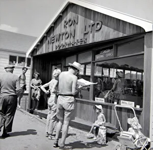 Holidaymakers study the form guide at a betting shop in the form of a wooden chalet