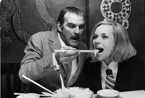 Honor Blackman and Stanley Baker eating food with chopsticks in Chinese restaurant
