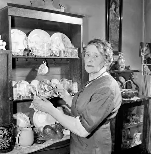 House wife arranging nik-naks on Welsh dresser. D5038