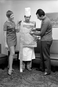 Humour. Man and woman covering a man in a Chefs uniform in plastic hearts