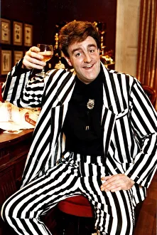 00492 Prints: Iain McColl actor in black and white striped suit raising glass whisky toast STV Hogmanay