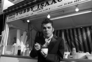 Actions Prints: Ian Dury outside the East End stall of Tubby Isaacs eating bowl of Jellied eels