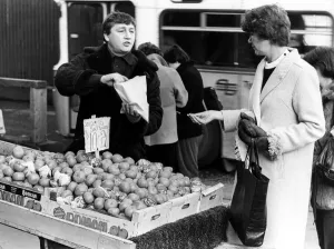 00496 Prints: Illegal street trader tommy Quinn makes a sale before having to move on 31st January 1981