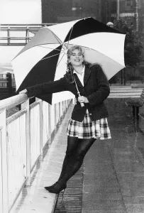 Imogen Stubbs Actress holding up Umbrella and leaning back while holding on to railing