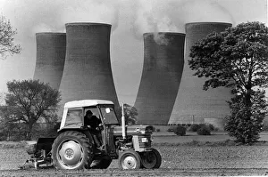 Where industry and agriculture meeta tractor at work under the shadows of the giant