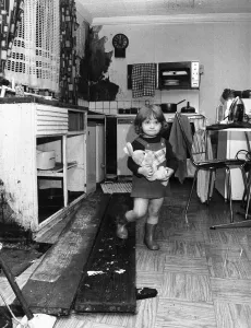 Loneliness Prints: Interior view of a London terraced house showing a child in the kitchen March 1983