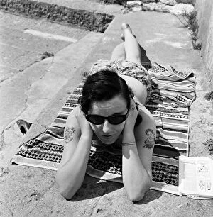 01227 Collection: Irene Redpath shows of her tattoos as she relaxes on the beach. 11th June 1962