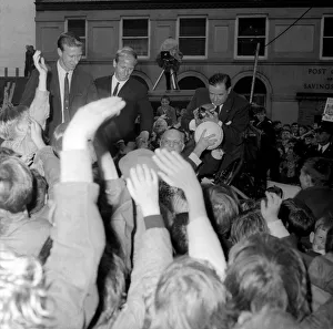 Jack and Bobby Charlton look over-awed as youngsters crowd around the car taking them to