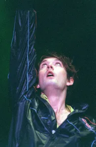 00081 Prints: Jarvis Cocker of pop group Pulp on stage at T in the Park on Sunday with arm raised in