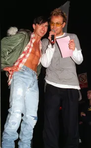Jason Donovan at Mr Gay UK singing into microphone holding pink piece of paper with man