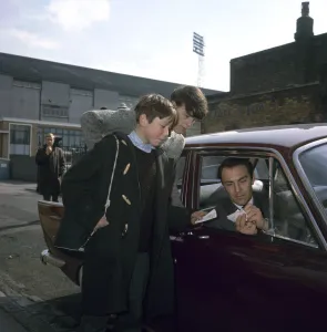 Spurs Prints: Jimmy Greaves of Tottenham Hotspur signs autographs for young fans as he leaves White