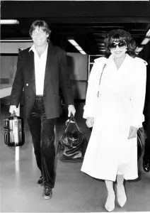 Joan Collins actress with boyfriend Bill Wiggins arriving at Heathrow Airport April