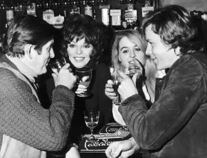 Joan Collins Actress enjoying a drink with Ray Barrett Sinead Cusack