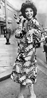Joan Collins carrying electric guitar at the Extravaganza 70s fashion exhibition