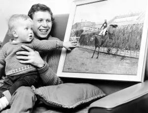 Jockey Brian Fletcher pictured showing his son Andrew a painting of Red Rum landing over